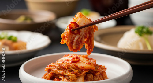 Close up of chopsticks holding spicy cabbage kimchi for healthy food