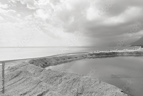 Fototapeta Naklejka Na Ścianę i Meble -  Coastal landscape with a sandy shoreline and a shallow water pool near the sea. Calm water surface