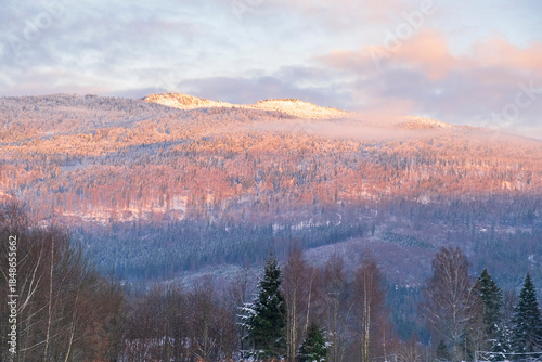 Gentle winter sunlight illuminating distant mountains and forested hills.