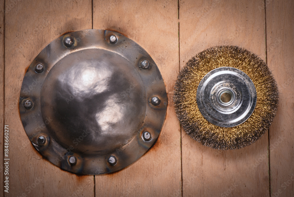 Fototapeta premium Shield boss manufacturing and polishing with angle grinder on wooden background.