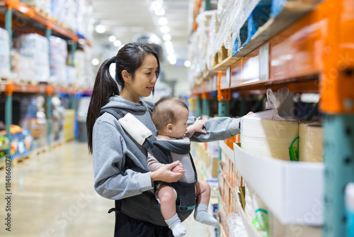 Mother carrying baby in supermarket shopping aisle