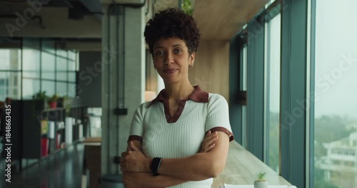 Assertive woman with open posture near window in professional environment