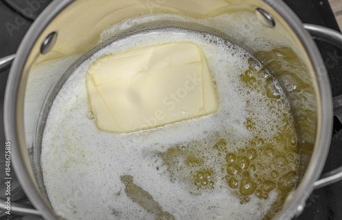 Canvas Print Clarify the butter in a pot, the butter cube melts the ice due to the temperatur