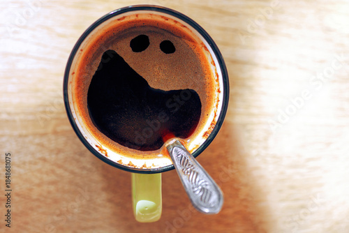 Pareidolia cup of black coffee with funny crazy smile
