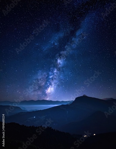 Stunning view of the Milky Way arching over dark, layered mountain silhouettes at night.