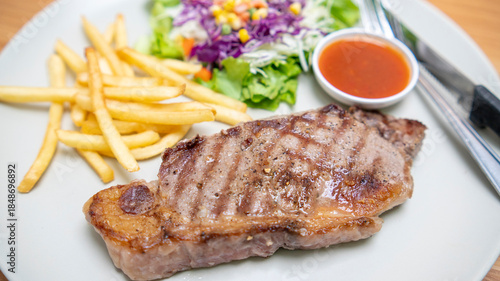 Juicy grilled striploin steak served with golden French fries fresh vegetable salad and side of tangy red sauce. 