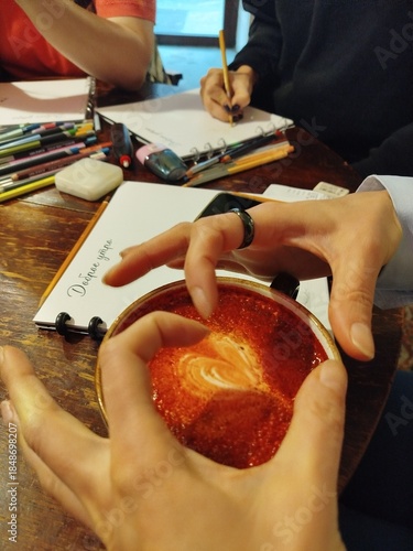 Hands creating latte art in a cozy cafe setting