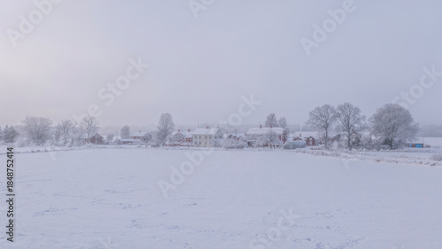 Farm barn and house in a cold winter landscape with snow and frost
