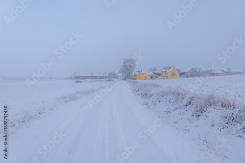 Farm barn and house in a cold winter landscape with snow and frost