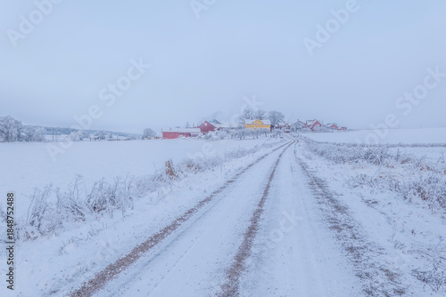 Farm barn and house in a cold winter landscape with snow and frost