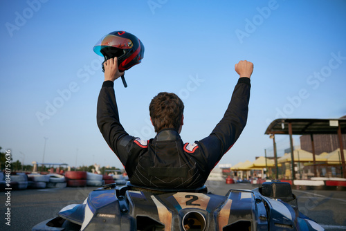 Obraz na plátně A go-kart racer raises their helmet in triumph after winning a race