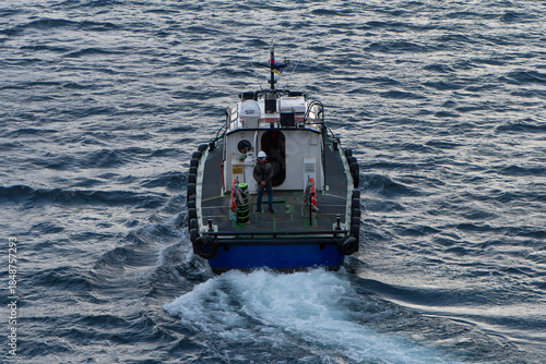 Aerial view of a boat cutting through the choppy, dark blue ocean waters, leaving a frothy white wake behind, Puerto Williams, Chile.