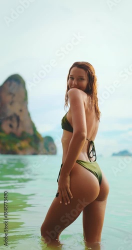 Bikini Woman Smiles and Turns Slowly in Sea with Cliffs Behind in Thailand