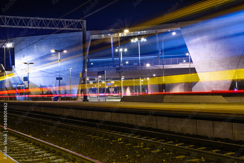 Obraz premium Train Light Trails At Modern Railway Station At Night, Suburban Public Transport And Mobility