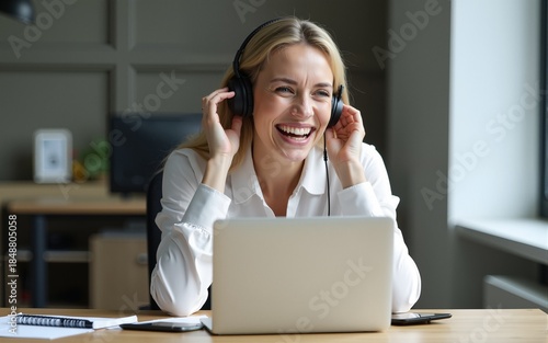 Portrait of overjoyed middle-aged business woman or teacher wear headphones sit at workplace desk with laptop laugh look aside. On-line counselling, e-learn, tutoring, videocall event, tuition concept