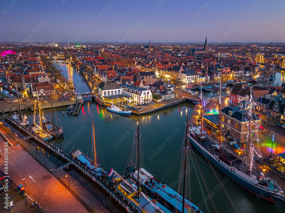 Fototapeta premium Aerial drone view of Harlingen harbour and illuminated waterfront at blue hour