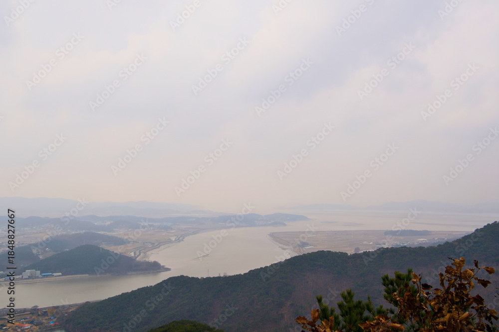 Obraz premium The view of the river and another mountain on a cloudy day from somewhere on the top of the mountain