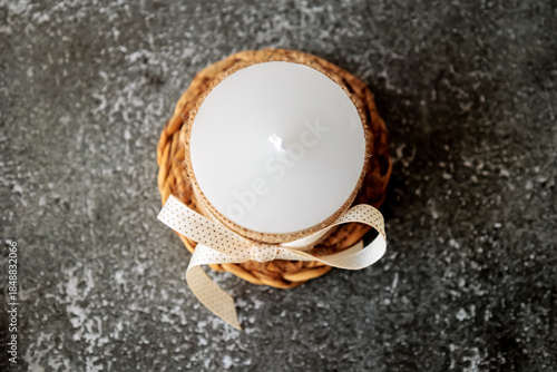 Wallpaper Mural White candle wrapped in rustic burlap and decorated with beige ribbon, placed on woven mat over dark textured background. Minimalist cozy decor for holidays, gift or relaxation Torontodigital.ca