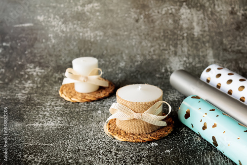 Wallpaper Mural Set of handmade white candles decorated with ribbon and burlap, with rolls of wrapping paper on dark textured background. Holiday or romantic gift idea in cozy minimal style Torontodigital.ca