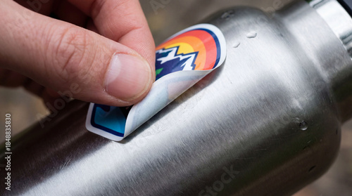 Youth removes colorful sticker from stainless steel bottle showing care for climate and supporting movement for change