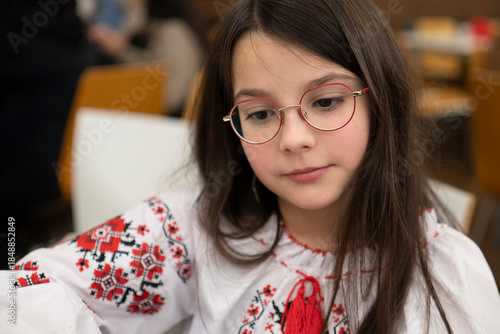 Thoughtful sad schoolgirl in glasses sitting in classroom, loneliness emotion concept