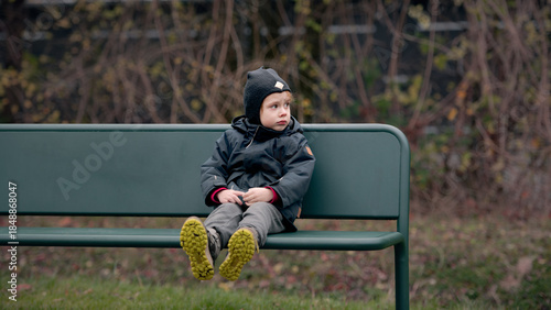 Thoughtful Child Waiting on a Bench in Autumn