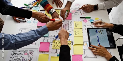 Engaging scene of diverse hands actively participating in a creative brainstorming session for a digital project, showcasing vibrant markers and sketches on a tabletop. SACTR