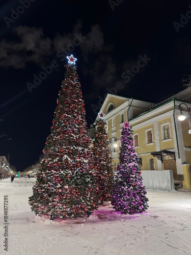 Snowy Night Public Square Christmas Tree Glowing With Purple Lights, Star Topper And Garland, Historic Municipal Building In Background, Crisp Winter Air, Soft Streetlight Glow,