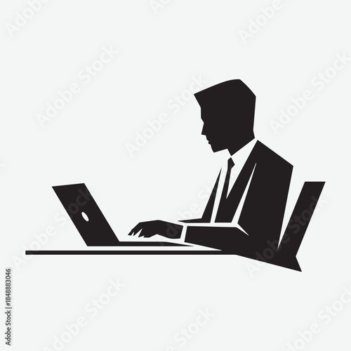 Silhouette of a businessman working on a laptop at a desk