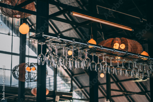Rows of Wine Glasses Hanging in a Modern Industrial Bar with Warm Lighting