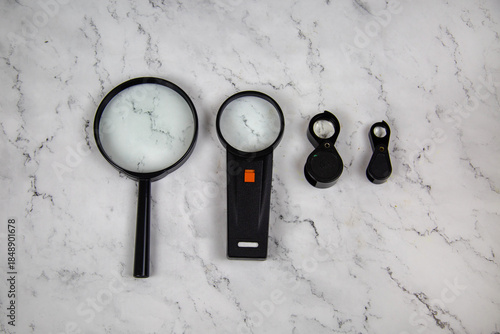 Magnifiers magnifying lenses of various sizes on a gray marble table. Tools, construction, production, design, structures.