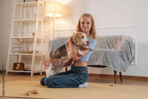 Casual time spending, wellness. Girl is with her dog on the floor in a cozy living room