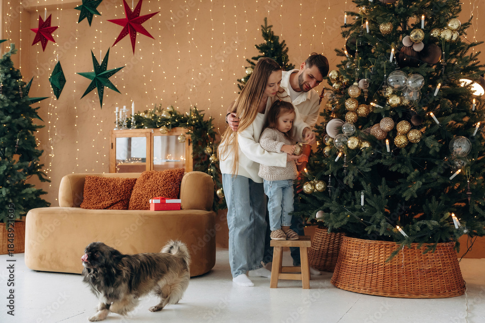 Naklejka premium Happy family with child and dog celebrating Christmas together at home with decorated tree
