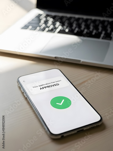 Mobile phone displays application approval on screen with laptop