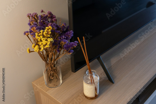 Dried flowers and reed diffuser on a wooden TV stand cozy evening living room, warm evening light