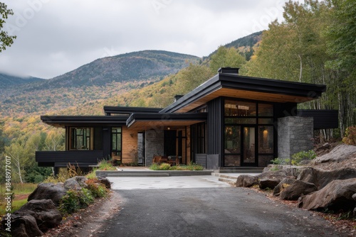 Modern house positioned near mountains with trees and clear sky in the foreground creating a natural setting at a scenic location during autumn