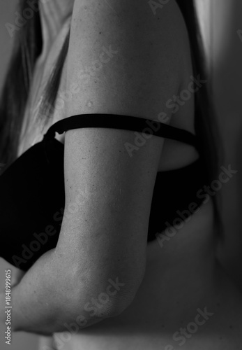Boudoir photo shoot of a girl. Black and white photo. Naked neck, shoulders and back of a young girl.