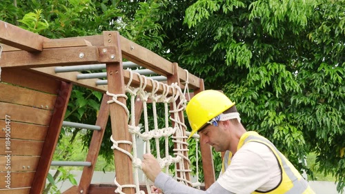 Male teacher inspects the wooden playground equipment climbing sets sports and recreational exercise activities children play with check the structure strength and prevent accidents for safety.