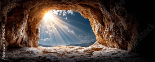 A stunning view from a cave, showcasing sunlight streaming through an opening, illuminating the rocky interior and contrasting with the blue sky.