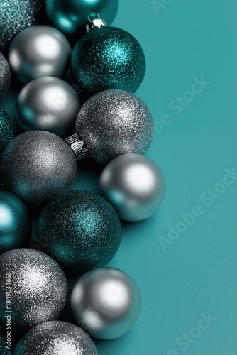 A pile of dark teal and silver Christmas ornaments on the left side against an isolated turquoise background.