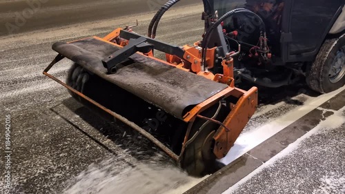 Snow removal machine clears roads during winter night in urban area
