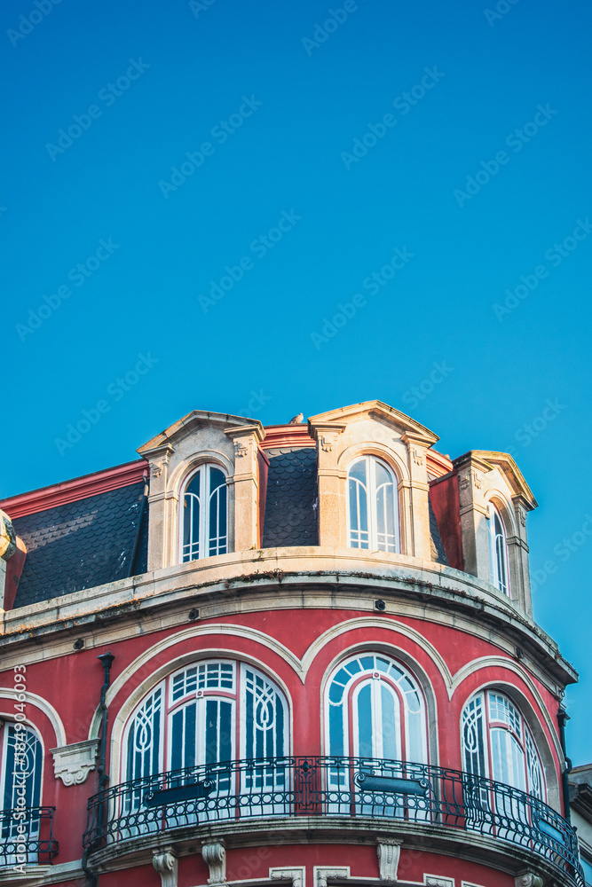 Obraz premium Prédio antigo vermelho com janelas arqueadas sob céu azul.