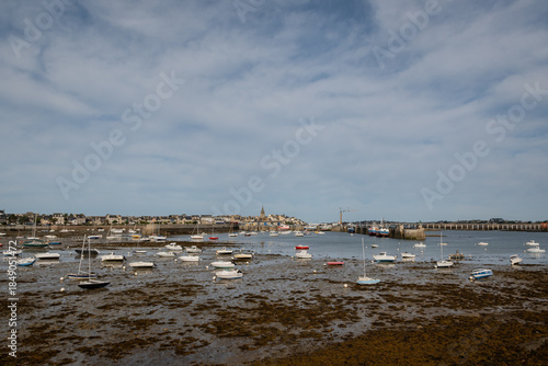 boats yachts and watercraft vessels lie beached in the sand bay in Port of Roscoff, Brittany France in low tide. Coastal town traditional French maritime village