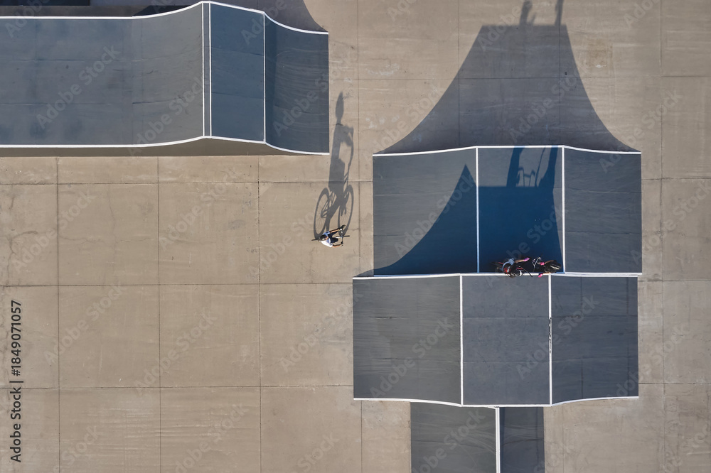 Fototapeta premium Biker performing tricks in a urban skatepark with ramps and shadows