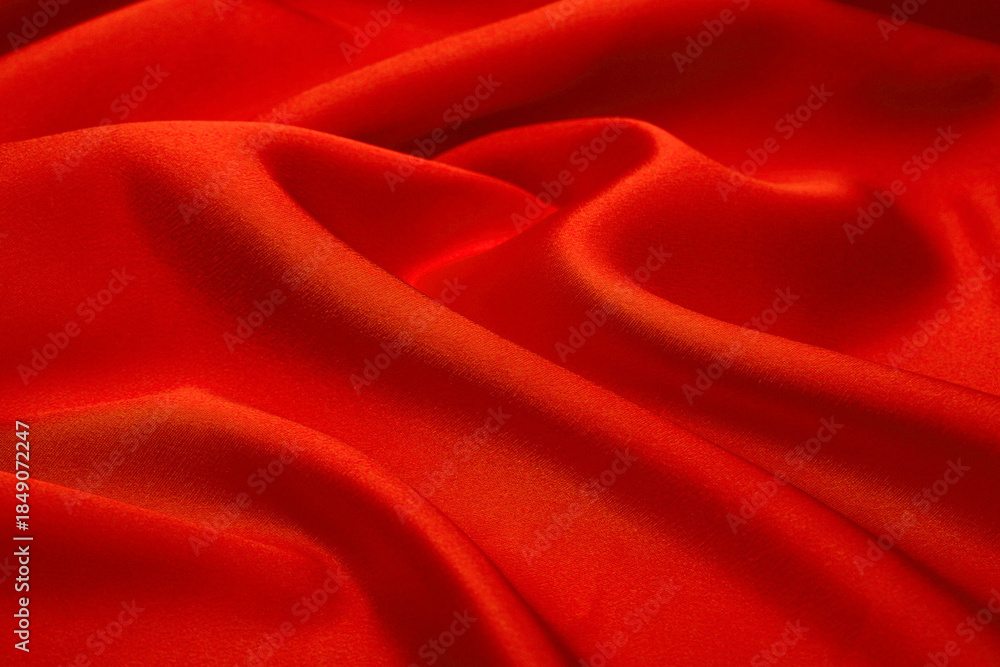 Obraz premium Bright red satin fabric texture with shimmering folds, luxurious silky textile perfect for glamorous design, fashion, beauty branding, and elegant packaging.