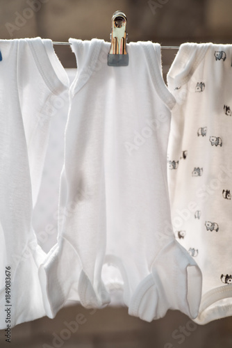 White baby bodysuits hanging in a row