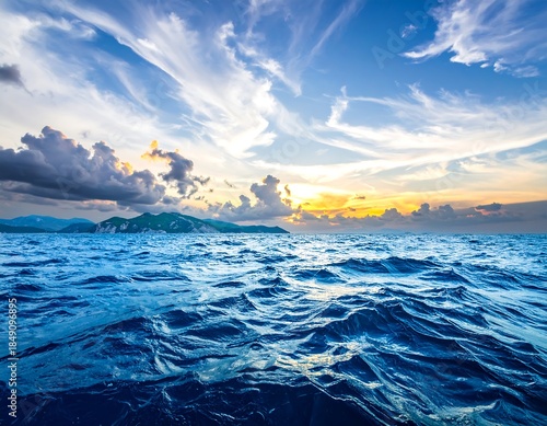 Ocean waves ripple under a wispy, bright sky at dusk; distant island is visible on the horizon