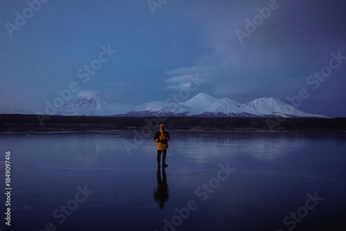 A Man on a Frozen Lake with a View of Kamchatka Volcanoes