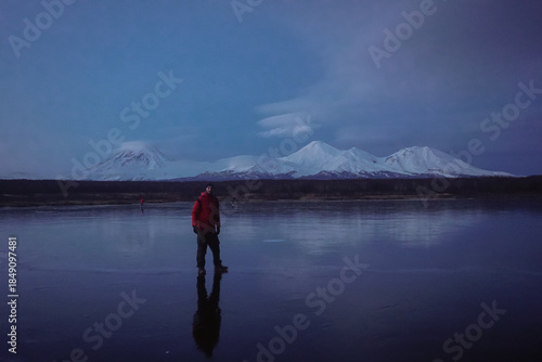 A Man on a Frozen Lake with a View of Kamchatka Volcanoes