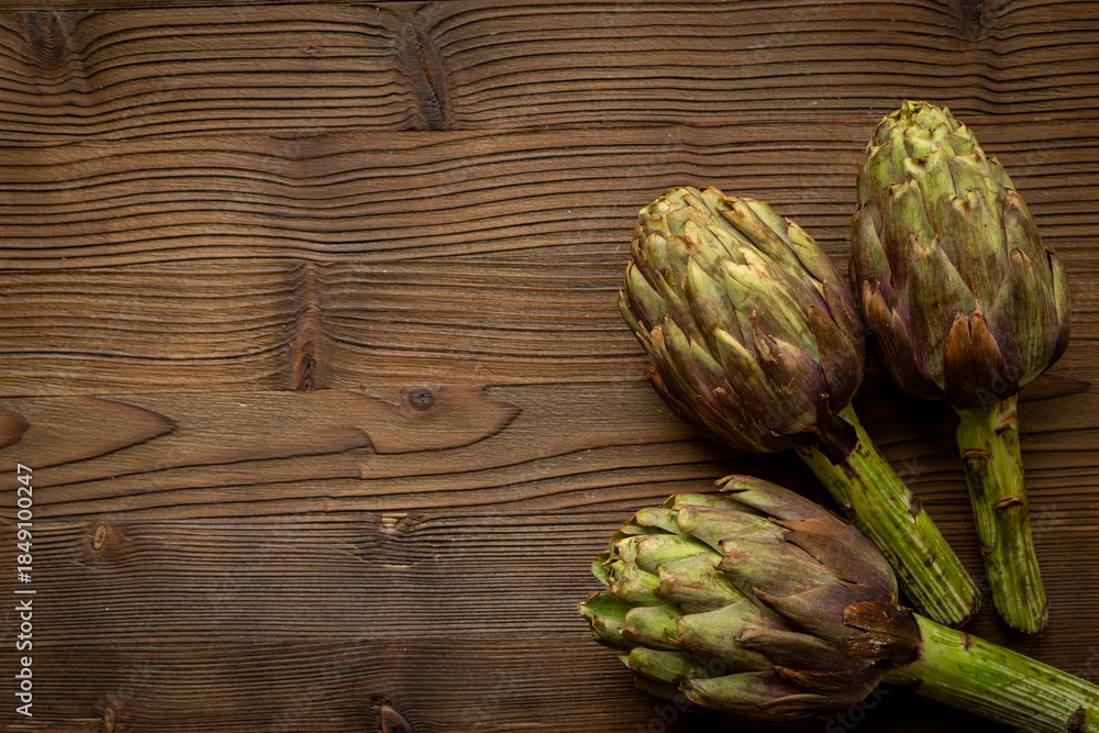 Obraz premium Whole heads of purple artichokes top view. Vegetables food ready to cook
